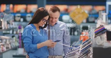 一对幸福的夫妇在电子商店里看着新的数码相机